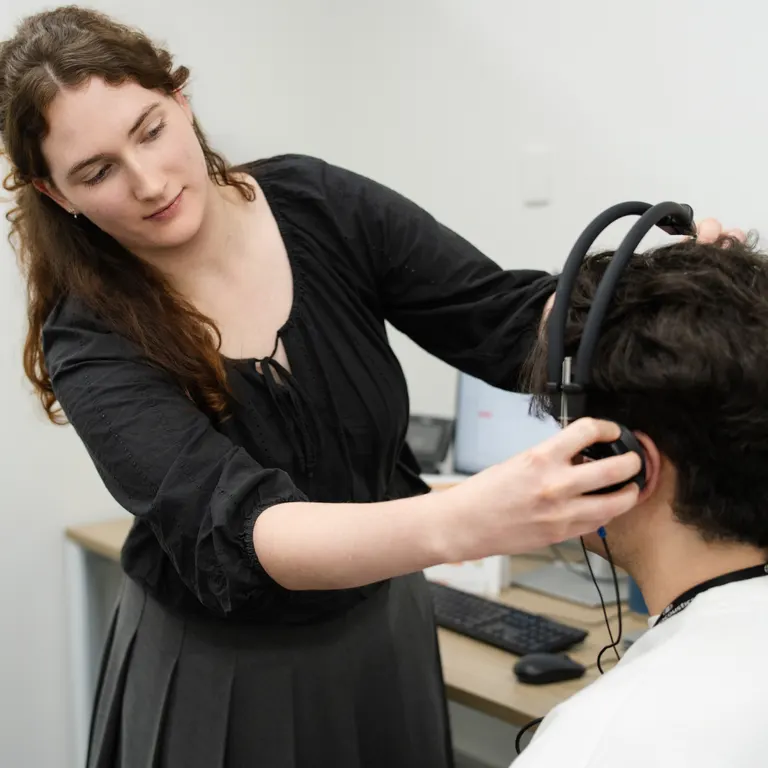 An audiologist fitting headphones on a patient for a hearing test