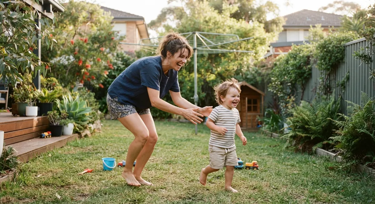 A parent playing with a toddler in a backyard