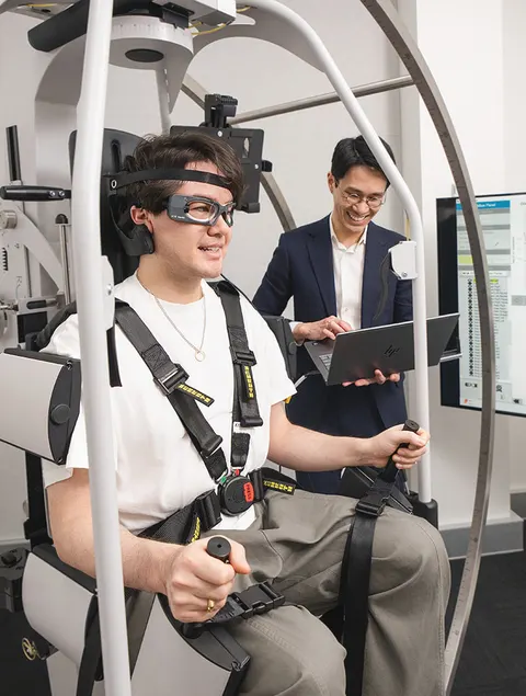 A patient wearing video-nystagmography goggles in the Rotundum positioning chair while a clinician reviews the recording