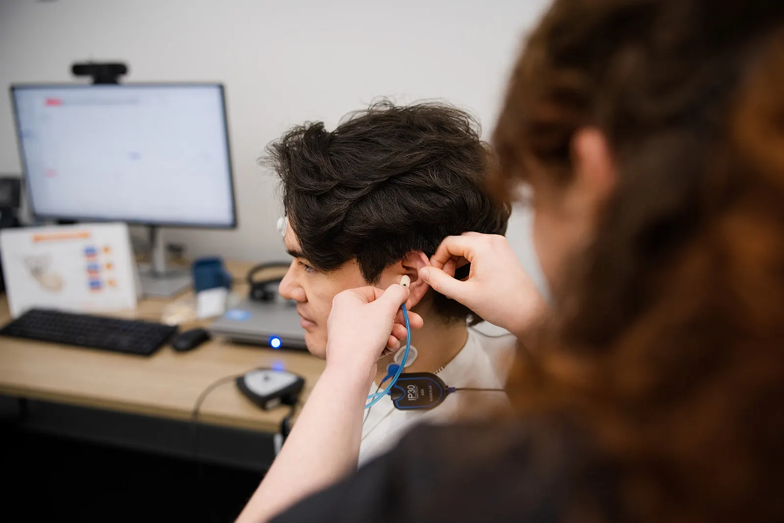 A clinician setting up vestibular evoked myogenic potential (VEMP) testing equipment